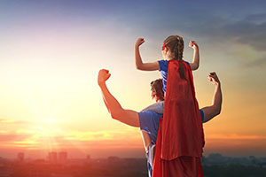 Happy loving family. Dad and his daughter playing outdoors. Daddy and child girl in an Superhero's costumes. Concept of Father's day.